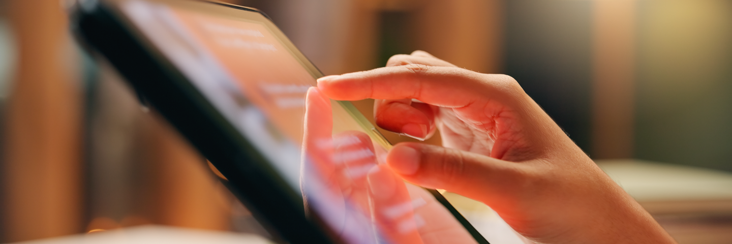 Manos sosteniendo una tablet con un feed de contenidos. Noticias UMLAC: comunicaciones institucionales de la universidad.